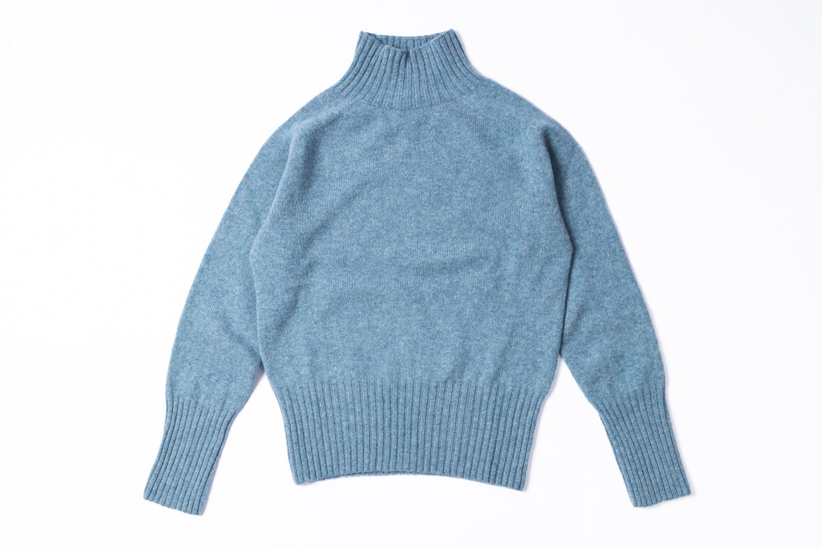 A light blue heathered knit turtleneck sweater with long sleeves and ribbed cuffs and hem, laid flat on a white background.