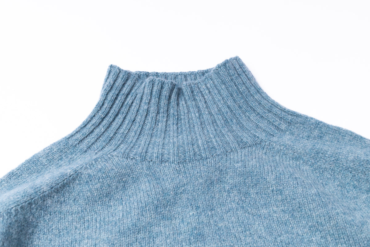 Close-up of a light blue ribbed knit turtleneck sweater on a white background.