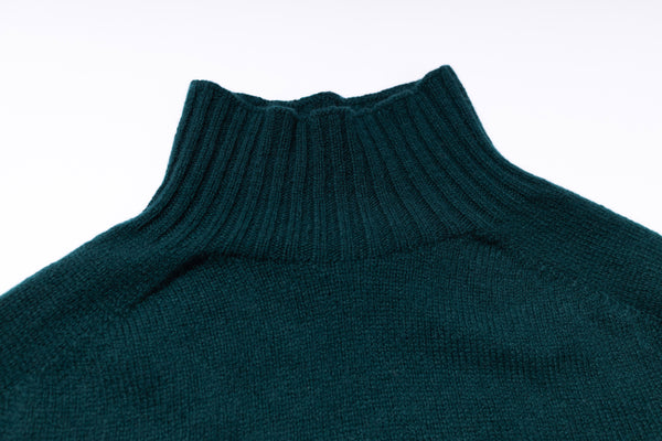 Close-up of a teal turtleneck sweater on a white background