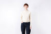 Person wearing a cream sweater and dark jeans against a white background
