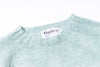 Close-up of a light blue sweater with a Harley label on a white background