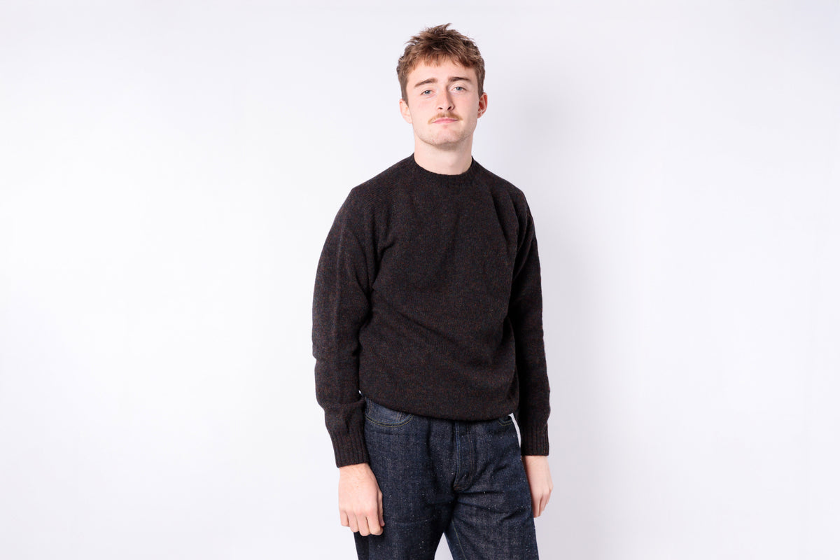 Person wearing a black sweater and dark jeans on a white background