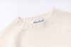 Close-up of a beige sweater with a 'Harley' label on a white background