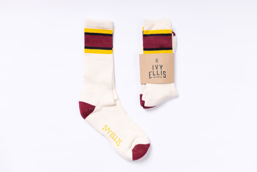 Pair of cream socks with red and yellow stripes on a white background, featuring the brand 'Ivy Ellis'.