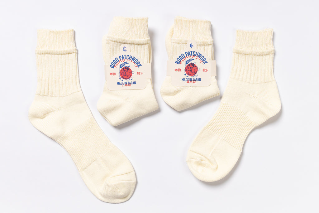 Set of cream-colored socks with brand logo on a light gray background
