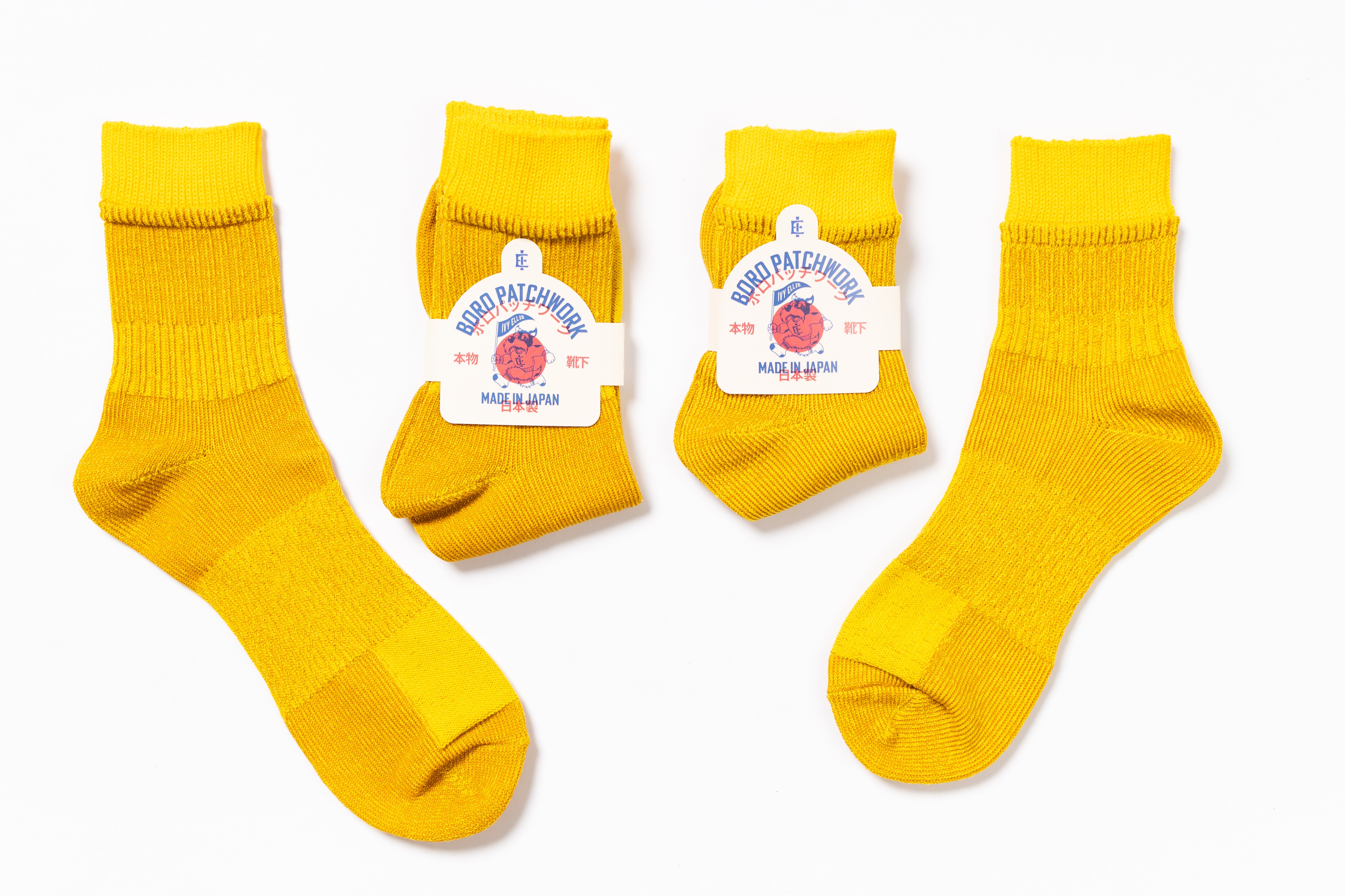 Four pairs of yellow socks with brand labels on a white background