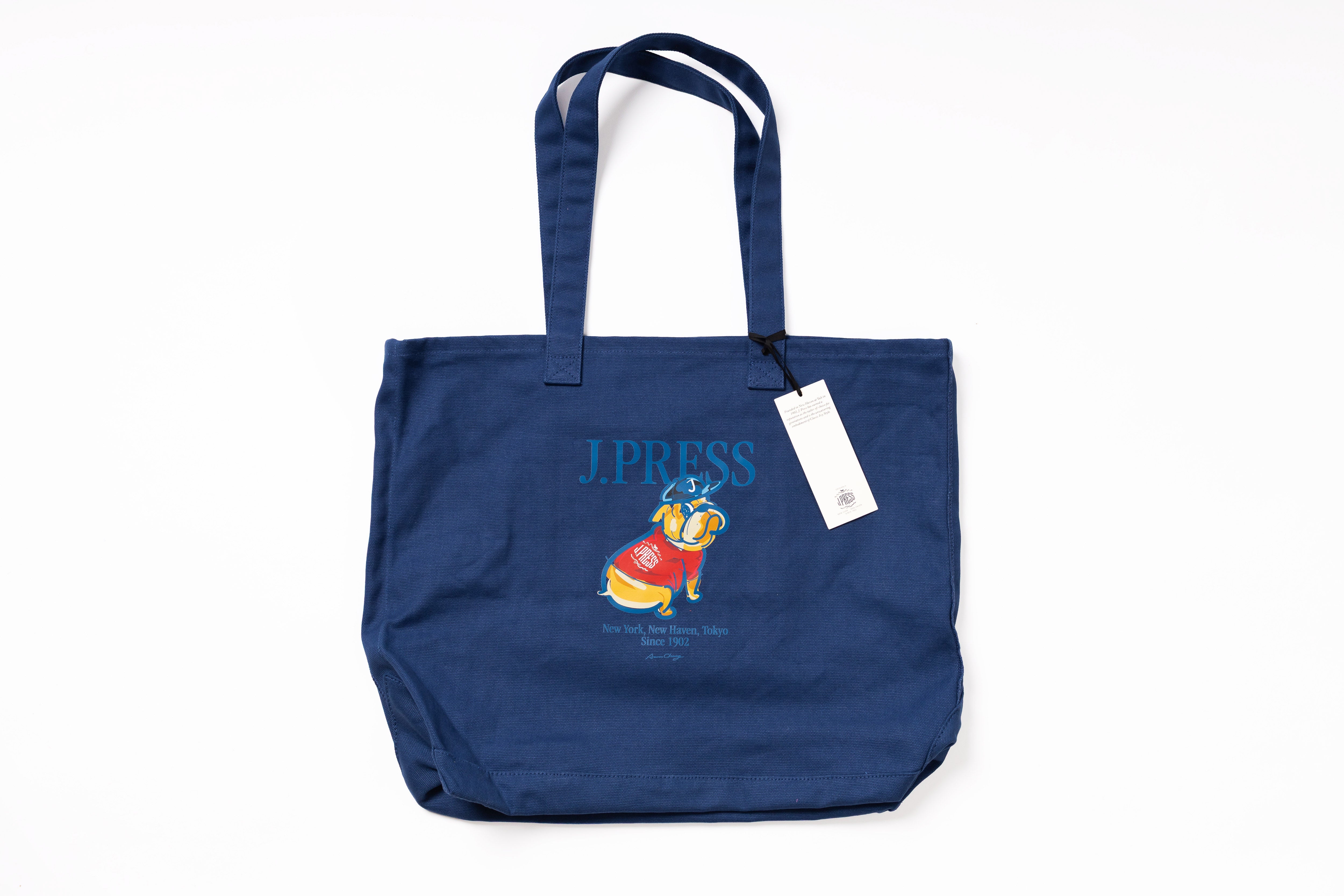 Blue tote bag with a character design and 'J Press' branding on a white background