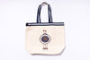 Beige tote bag with black straps featuring a logo on a white background