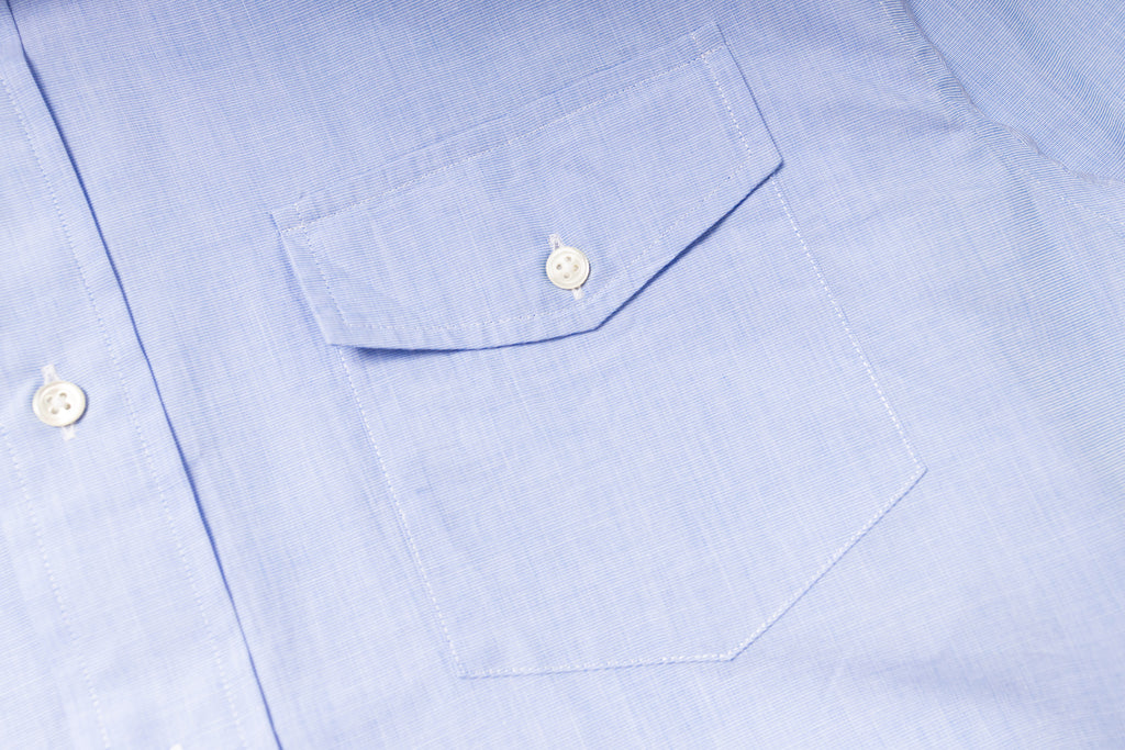 Close-up of a light blue shirt with a pocket and buttons.
