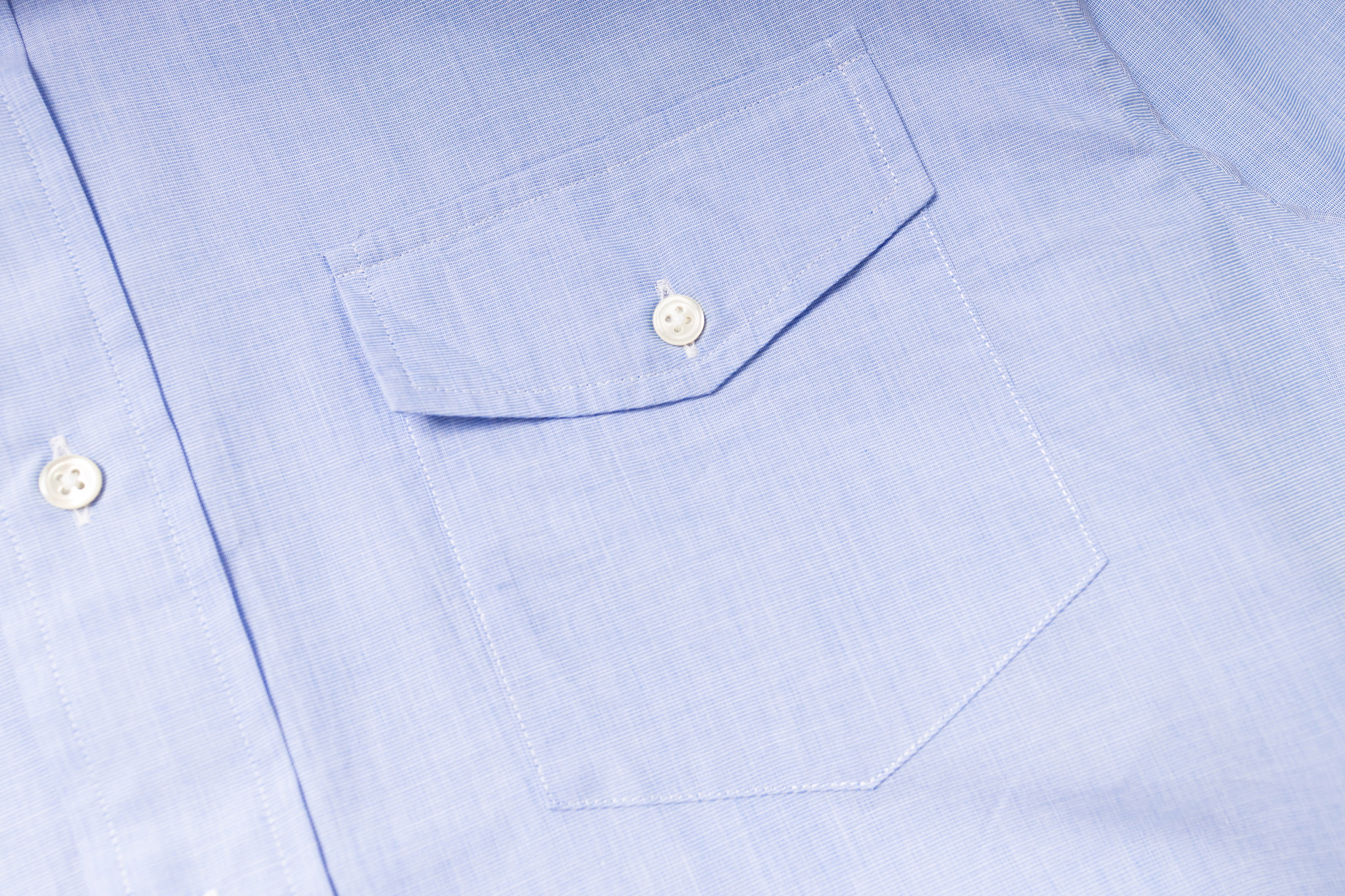 Close-up of a light blue shirt with a pocket and buttons.