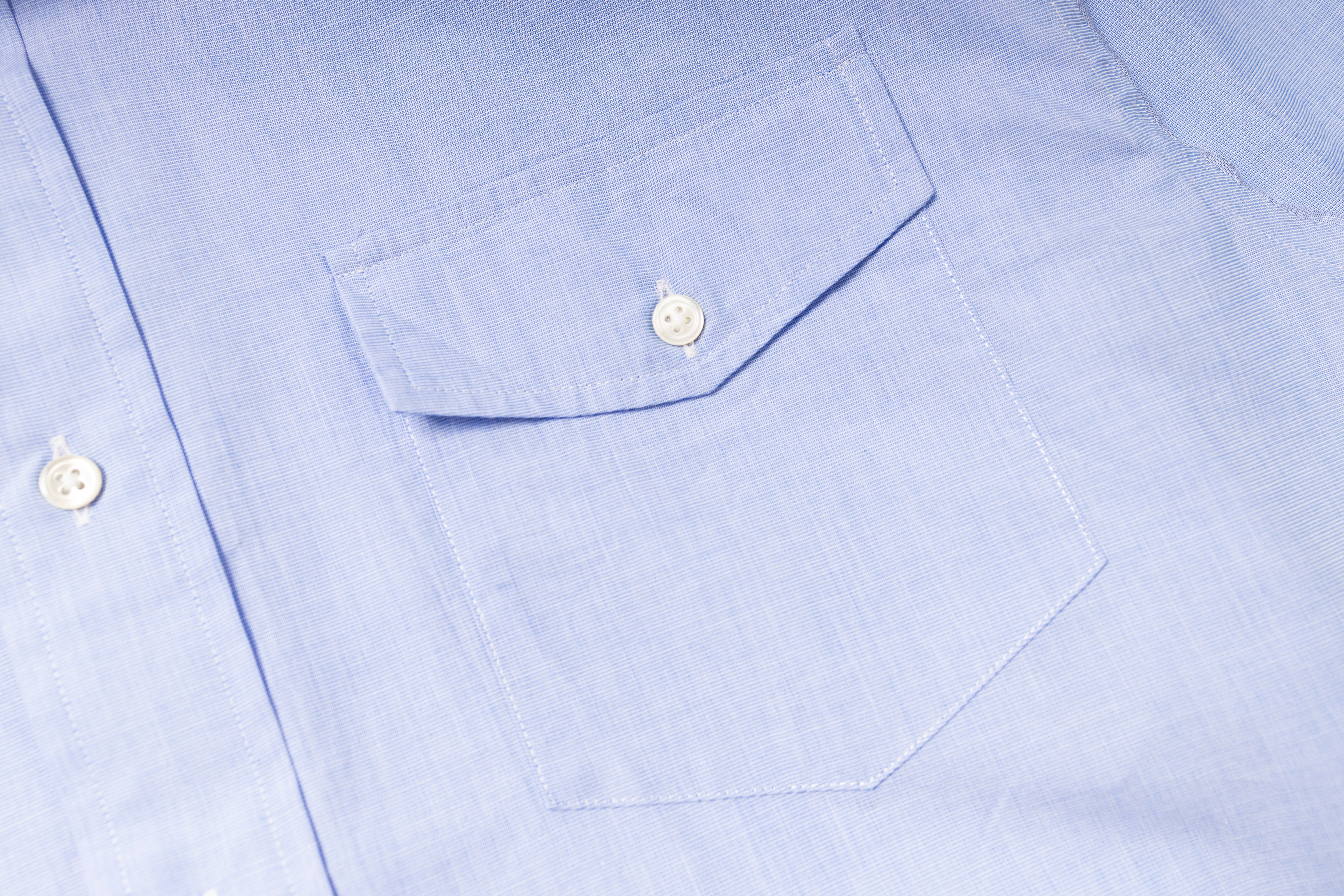 Close-up of a light blue shirt with a pocket and buttons.