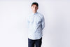 Person wearing a light blue shirt and dark pants on a white background