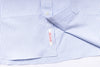 Close-up of a blue and white striped shirt with a brand label on a white background