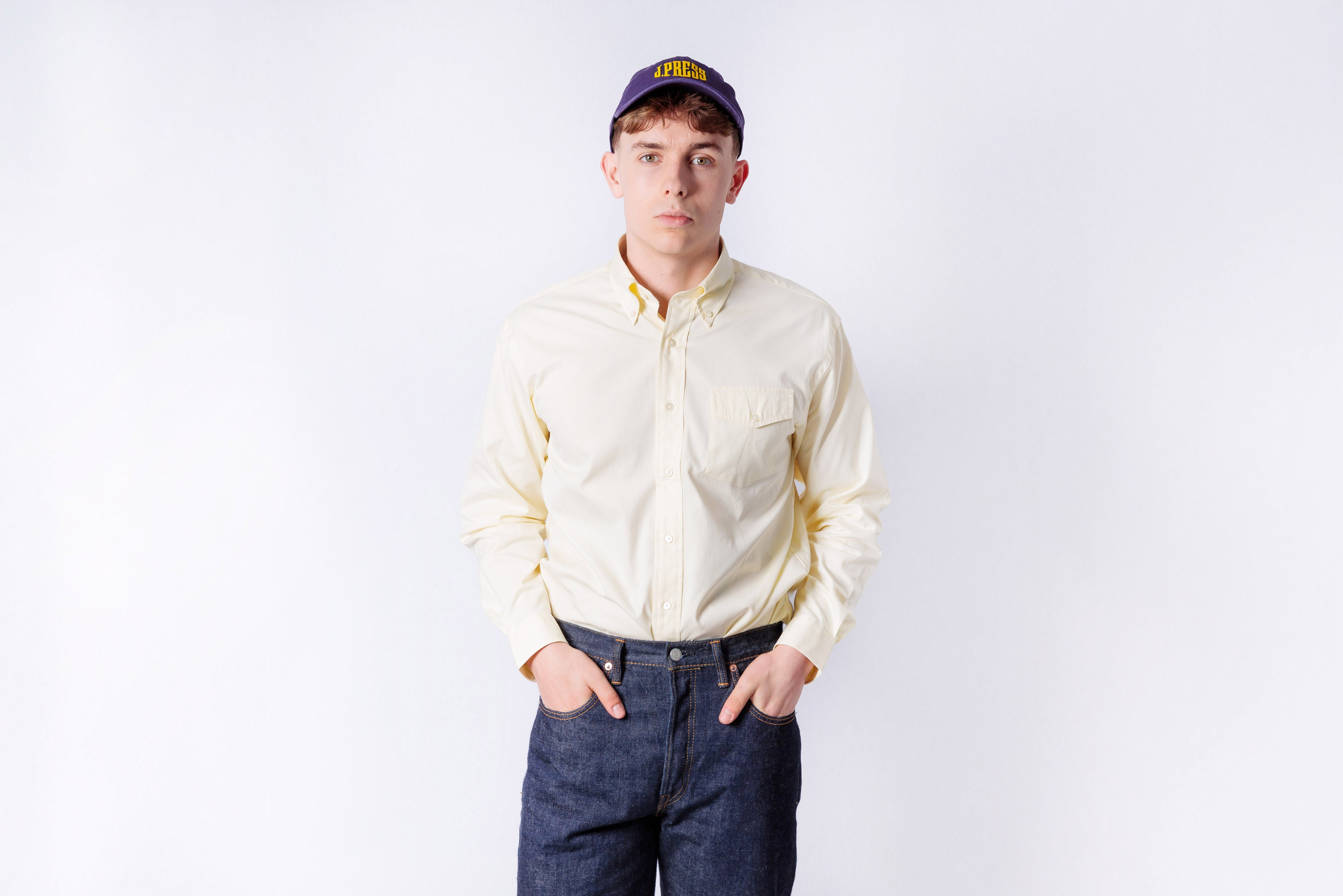 Person wearing a light-colored shirt and dark jeans on a white background