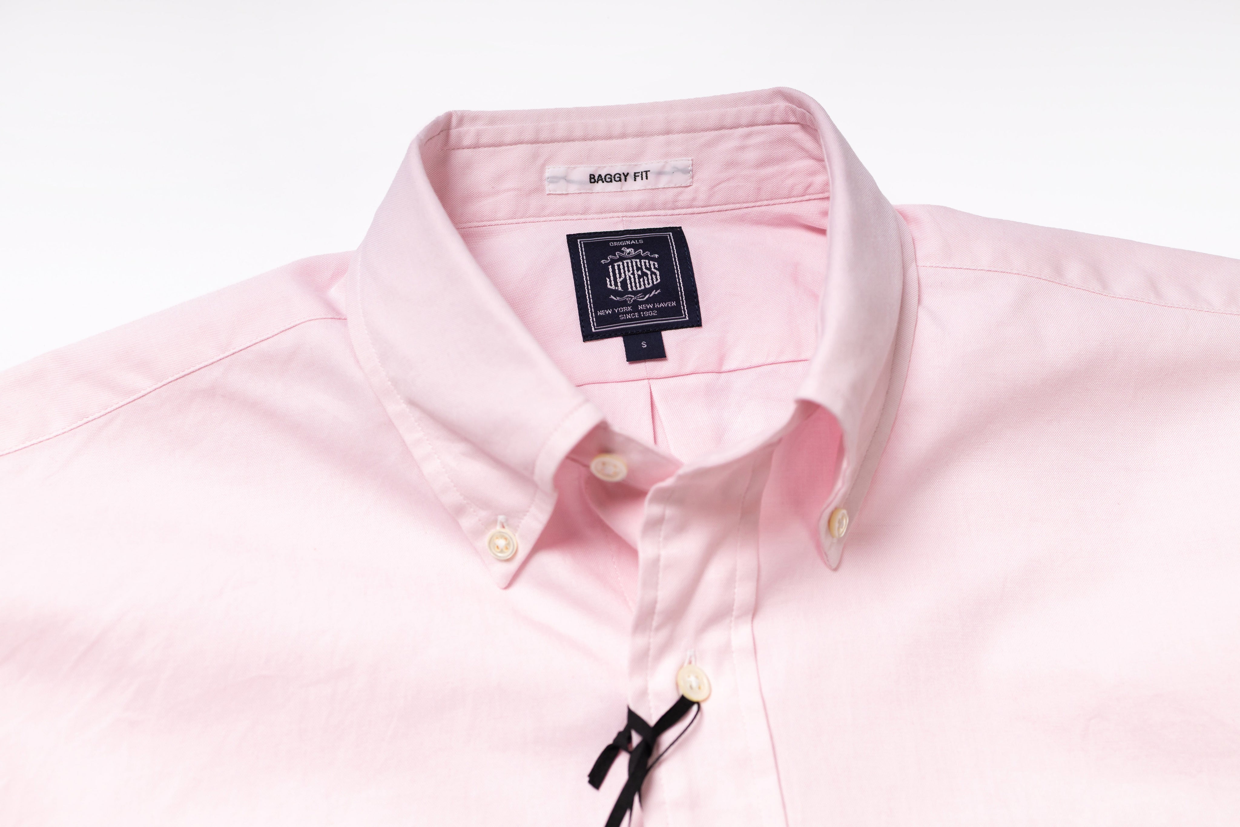 Close-up of a pink shirt with a brand label on a white background