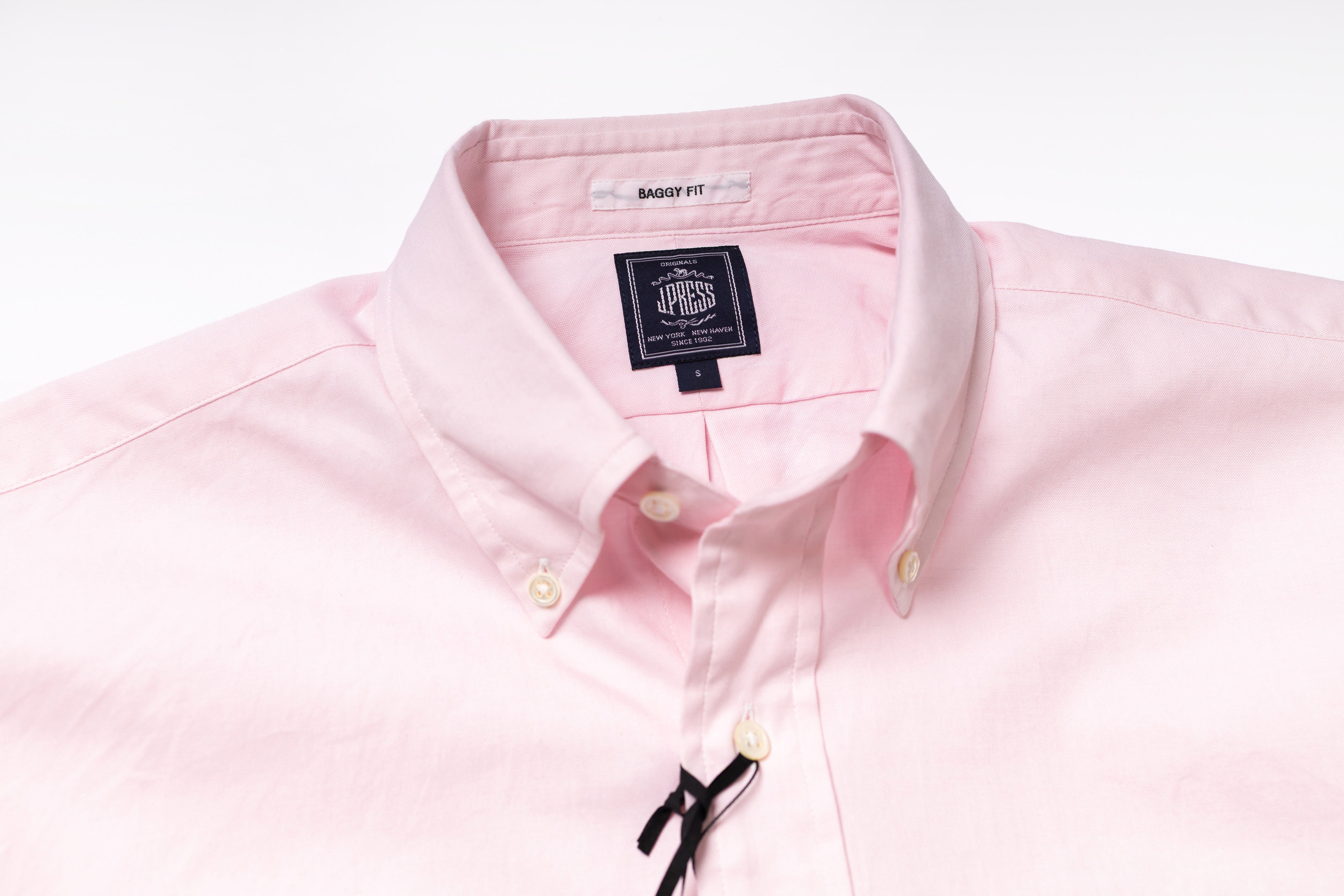 Close-up of a pink shirt with a brand label on a white background