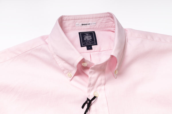 Close-up of a pink shirt with a brand label on a white background