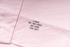 Pink fabric with embroidered text on a light pink background