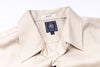 Close-up of a beige shirt with a brand label on a white background
