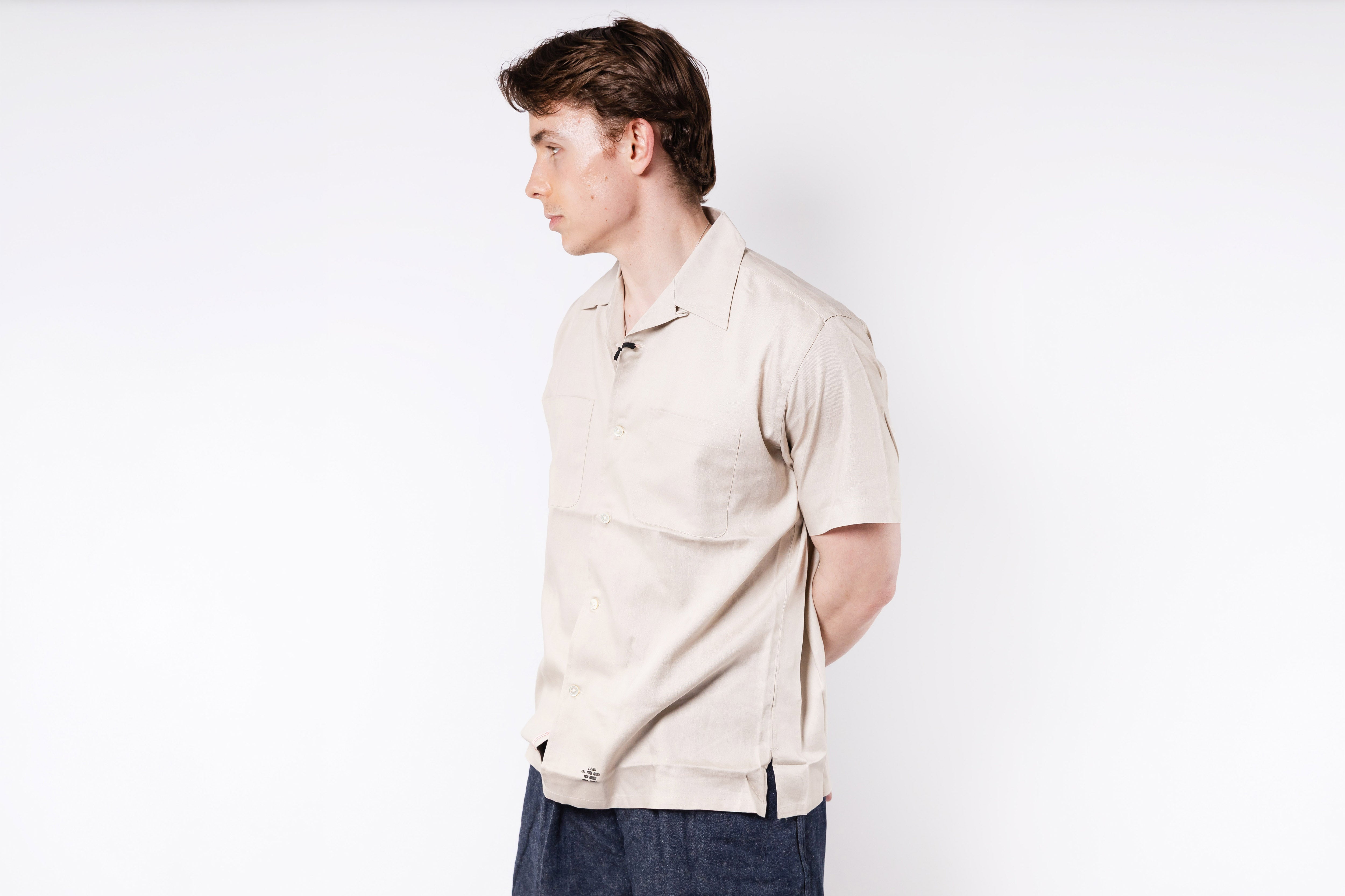 Man wearing a beige polo shirt against a white background