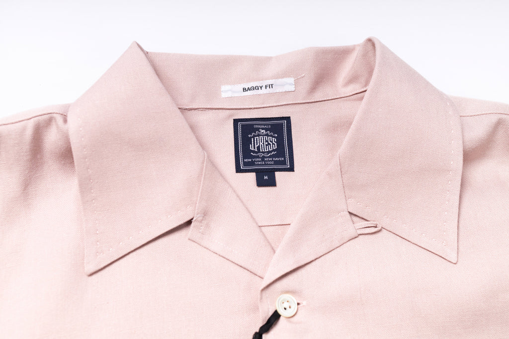 Close-up of a light pink shirt with a brand label on a white background