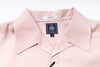 Close-up of a light pink shirt with a brand label on a white background