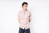 Person wearing a light pink shirt and dark pants on a white background