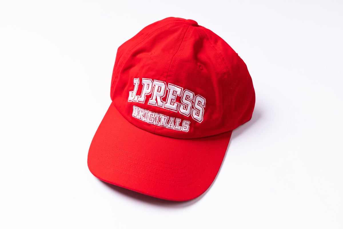 A red baseball cap with 'J PRESS ORIGINALS' embroidered in white on the front, shown on a clean white background.