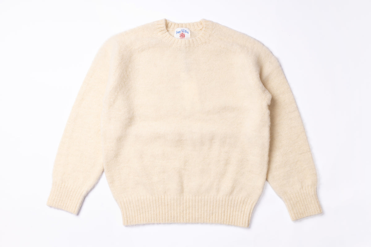 A cream-colored knit crewneck sweater with long sleeves and ribbed cuffs and hem, laid flat against a white background.