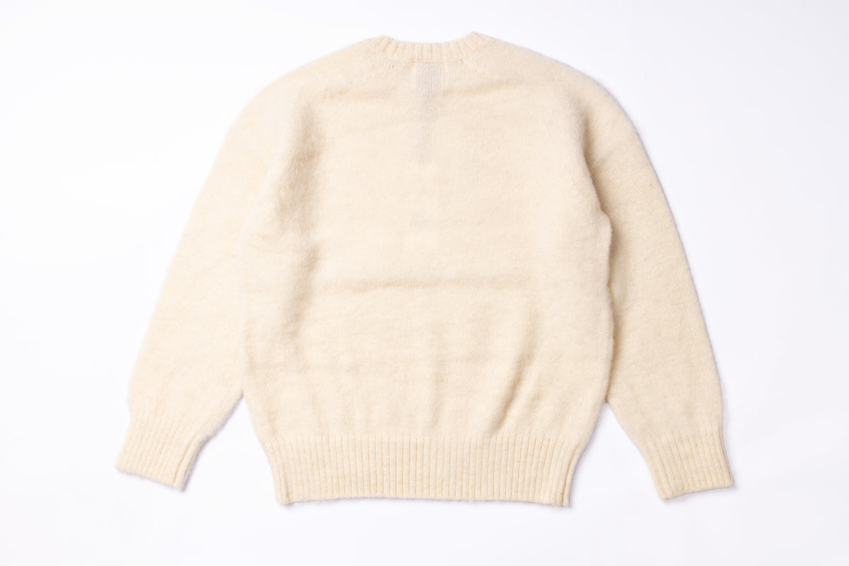 A cream-colored knit sweater shown from the back, laid flat against a clean white background.