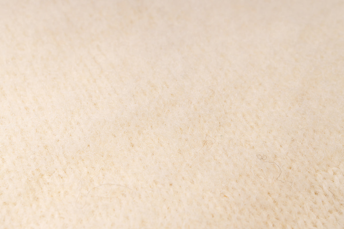 A close-up texture shot of a soft, fuzzy cream-colored fabric.