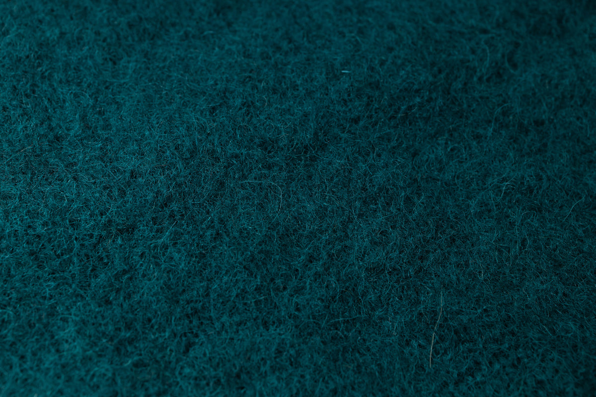 A close-up texture shot of a dark teal blue fuzzy fabric, showing the dense, soft pile of the material.