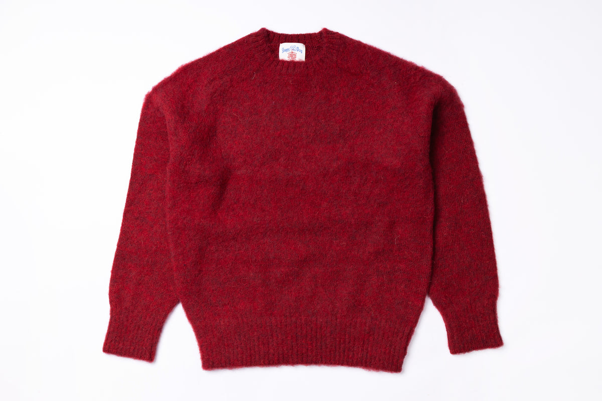 A dark red, long-sleeve knit sweater with a crew neck, laid flat against a plain white background.