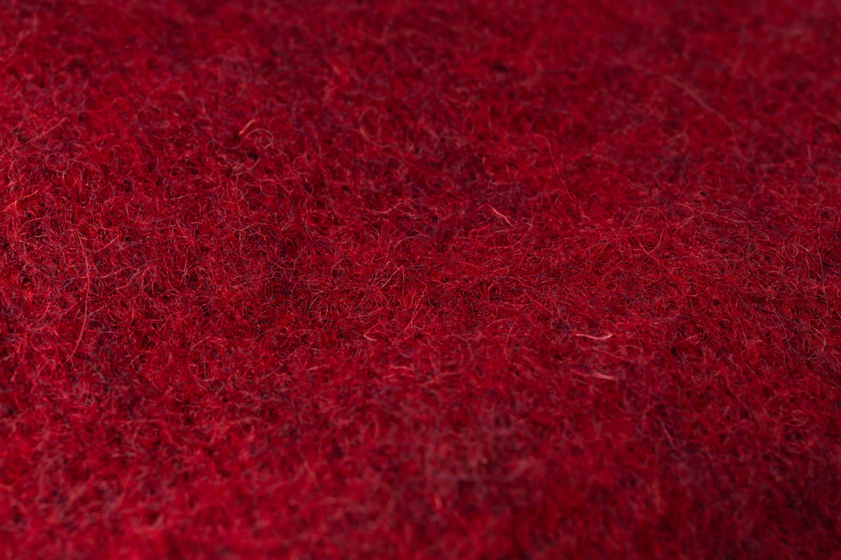 A close-up texture shot of a deep red, fuzzy fabric or felt material.
