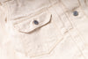 Close-up of a light beige canvas jacket featuring a chest pocket with a silver metal snap button and a matching snap button on the front placket.