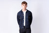 Man wearing a denim jacket over a white shirt on a light gray background