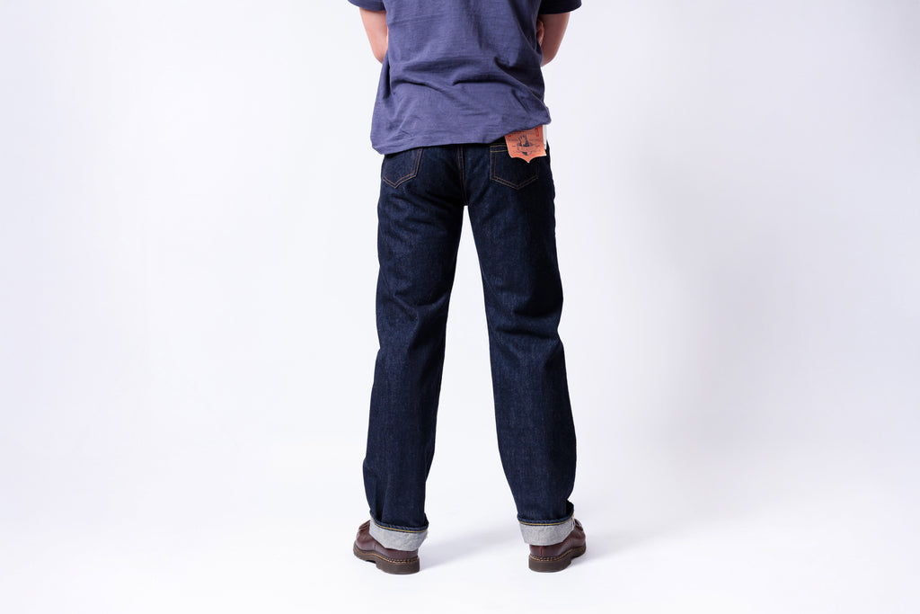 Person wearing dark blue jeans and a purple shirt on a white background