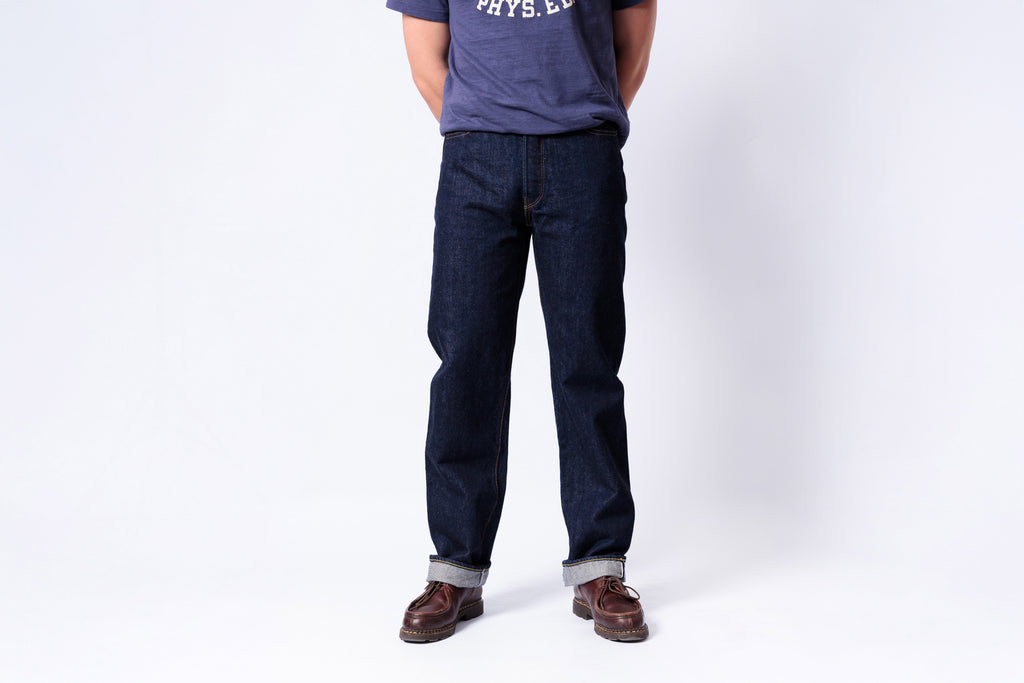 Person wearing dark blue jeans and a gray shirt on a white background