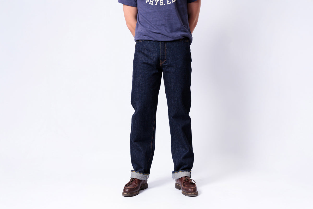 Person wearing dark blue jeans and a gray shirt on a white background