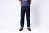 Person wearing dark blue jeans and a gray shirt on a white background