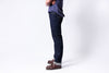 Person wearing dark blue jeans and brown shoes on a white background