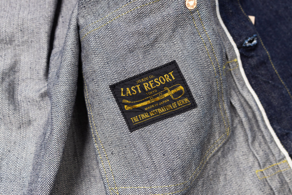 Gray denim jacket with 'The Last Resort' label on a blurred background