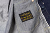 Gray denim jacket with 'The Last Resort' label on a blurred background