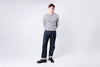 Man wearing a gray sweater and dark pants on a white background
