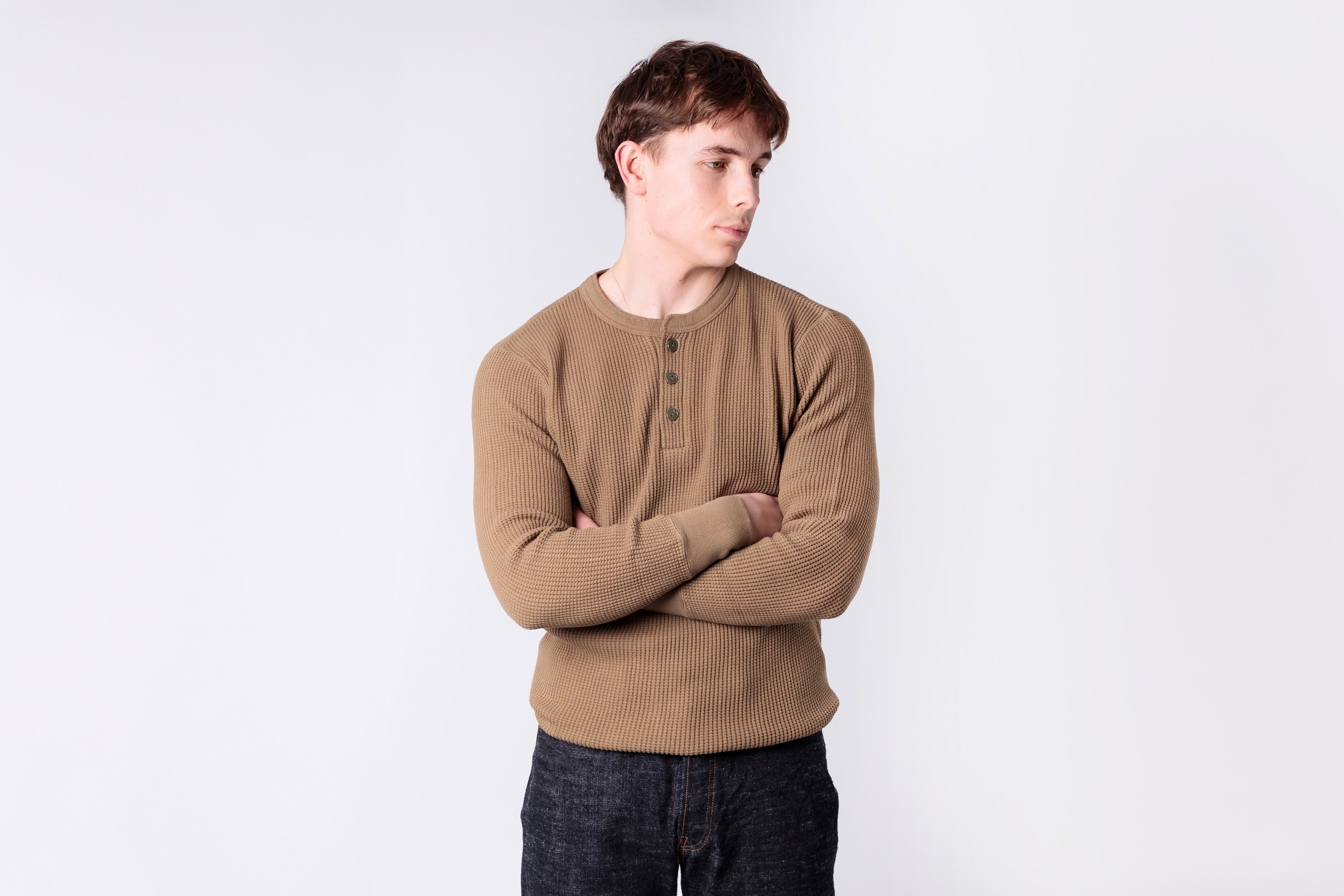 Person wearing a beige sweater against a white background