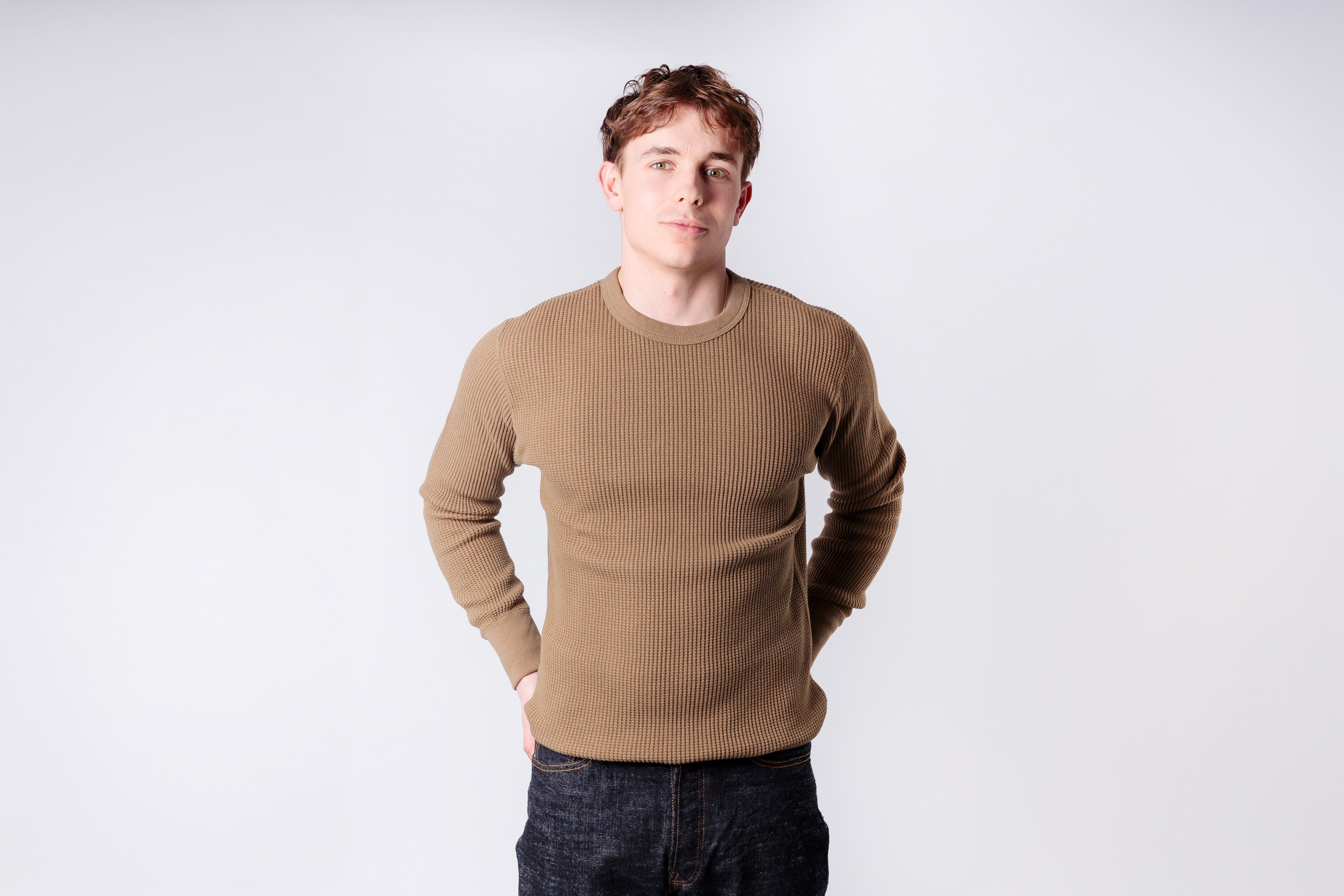 Man wearing a beige sweater against a white background