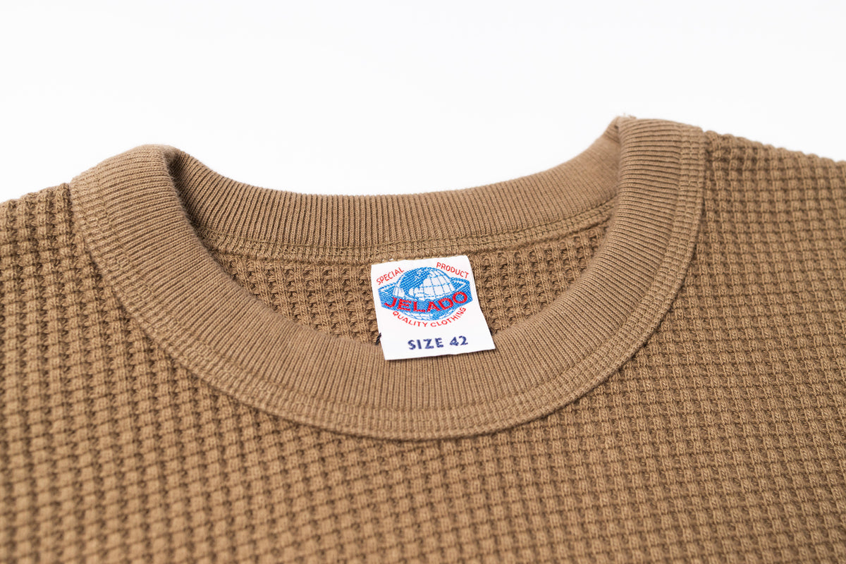 Close-up of a brown textured sweater with a size label on a white background