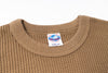 Close-up of a brown textured sweater with a size label on a white background