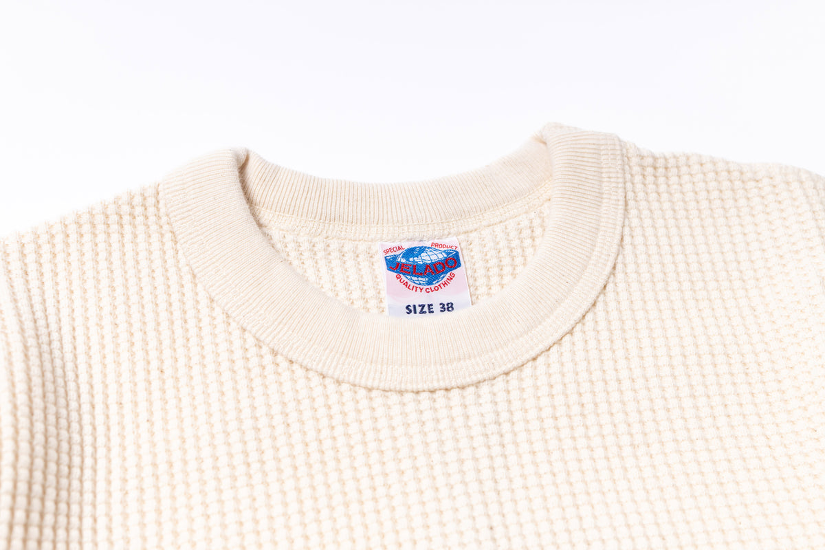 Close-up of a beige sweater with a size label on a white background