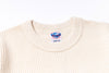 Close-up of a beige sweater with a size label on a white background